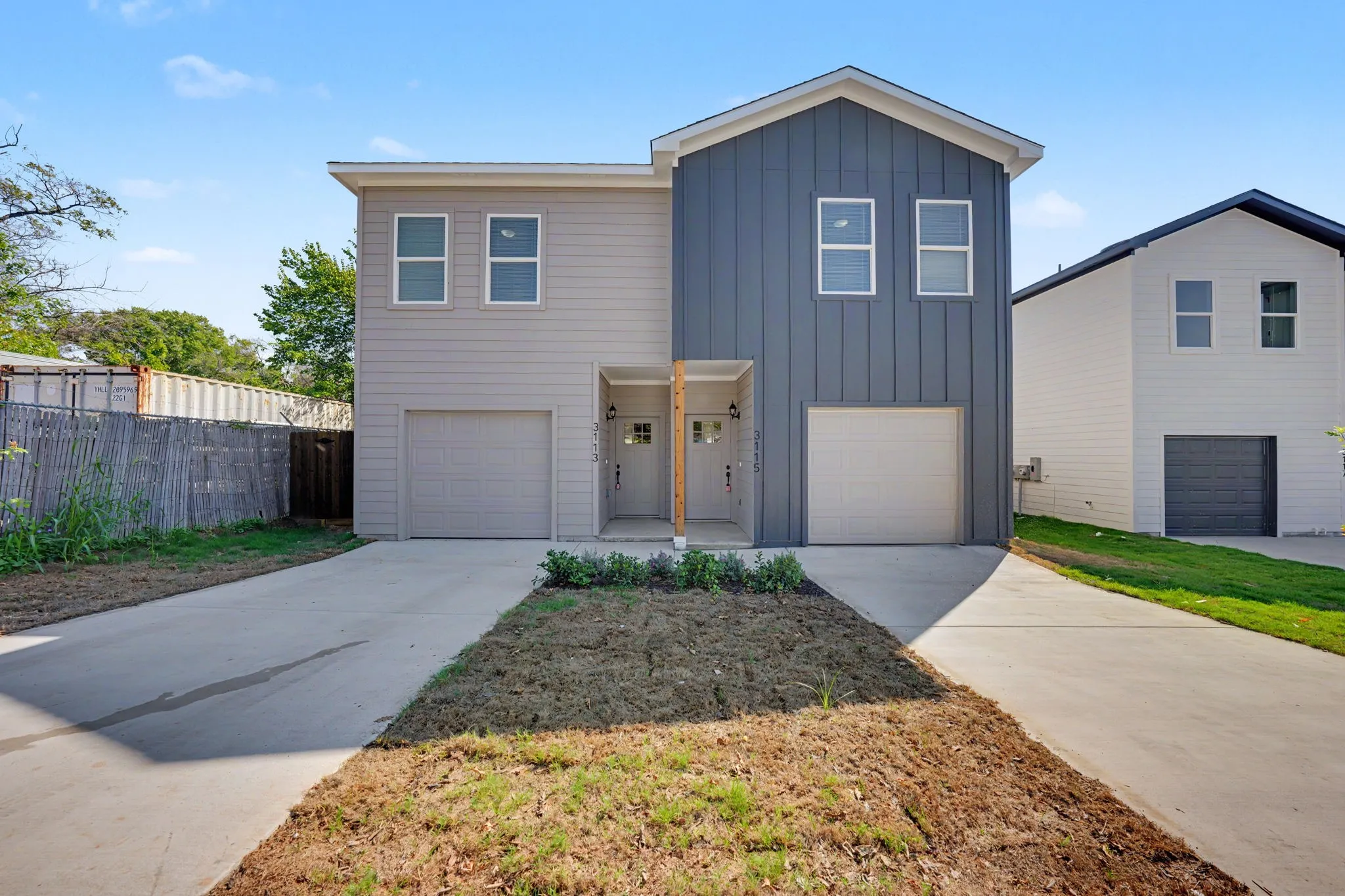 Modern duplex exterior featuring a light gray siding and a contrasting blue board and batten facade