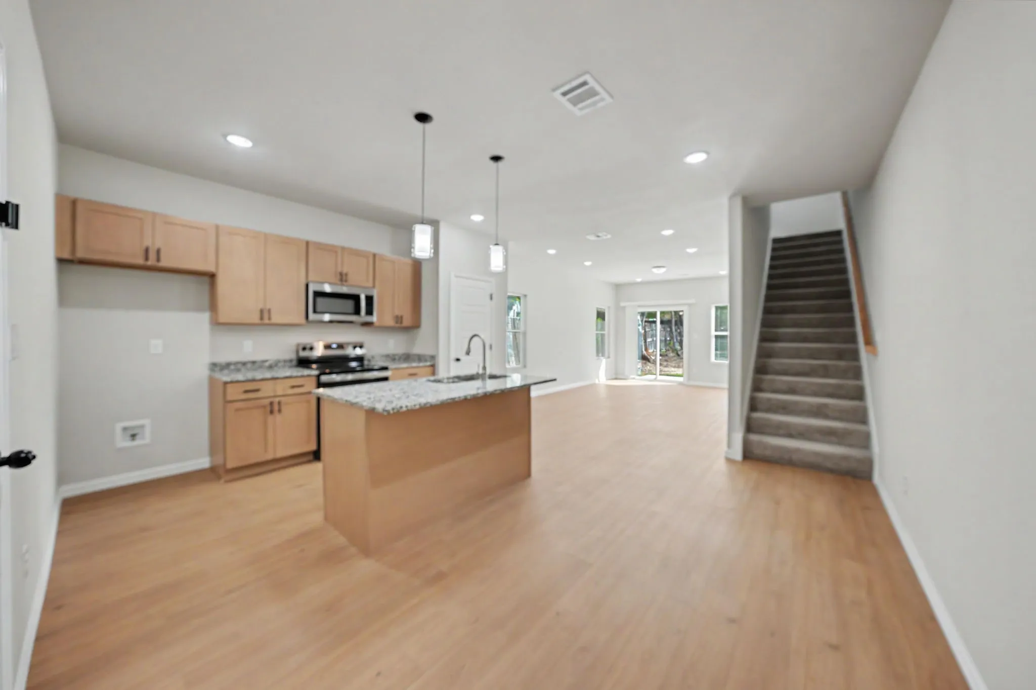 Open-concept living space featuring wood-finish flooring, recessed lighting, and a modern kitchen