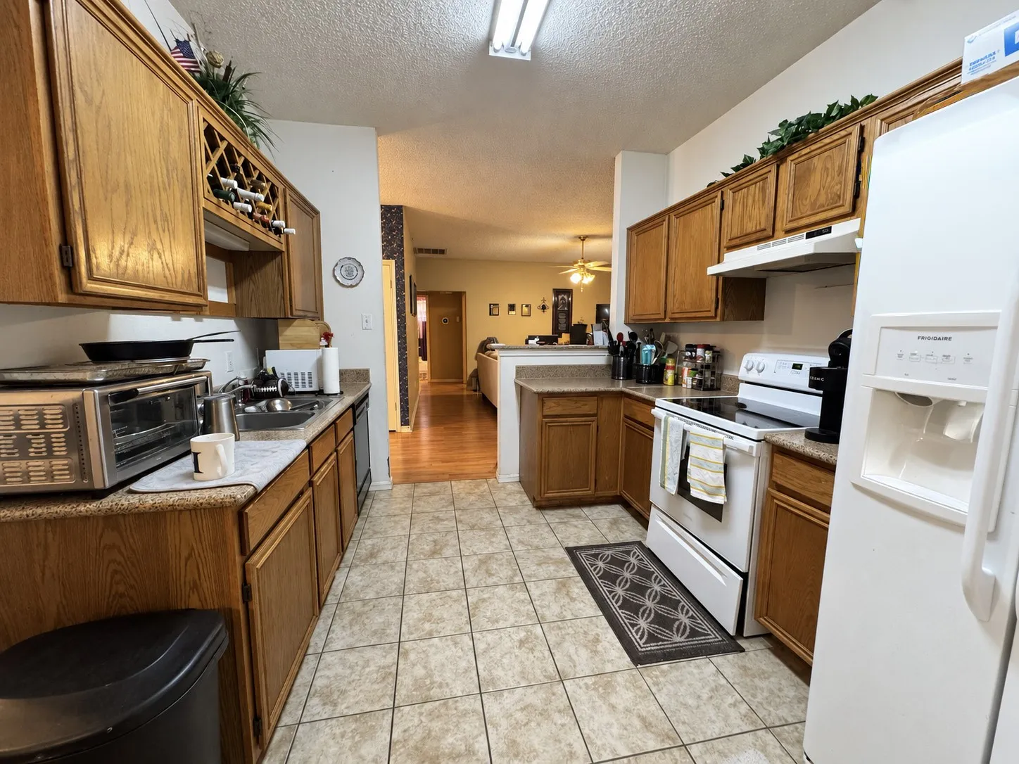 U-shaped kitchen featuring wood cabinetry, stone-finish countertops, tile flooring, and integrated wine storage