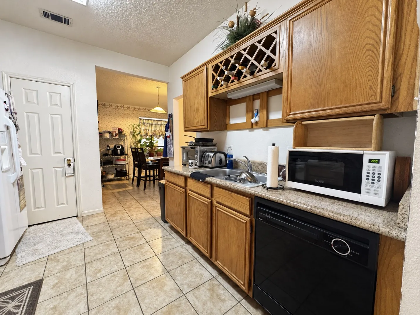 Kitchen featuring wood cabinetry, integrated wine rack, and a black dishwasher