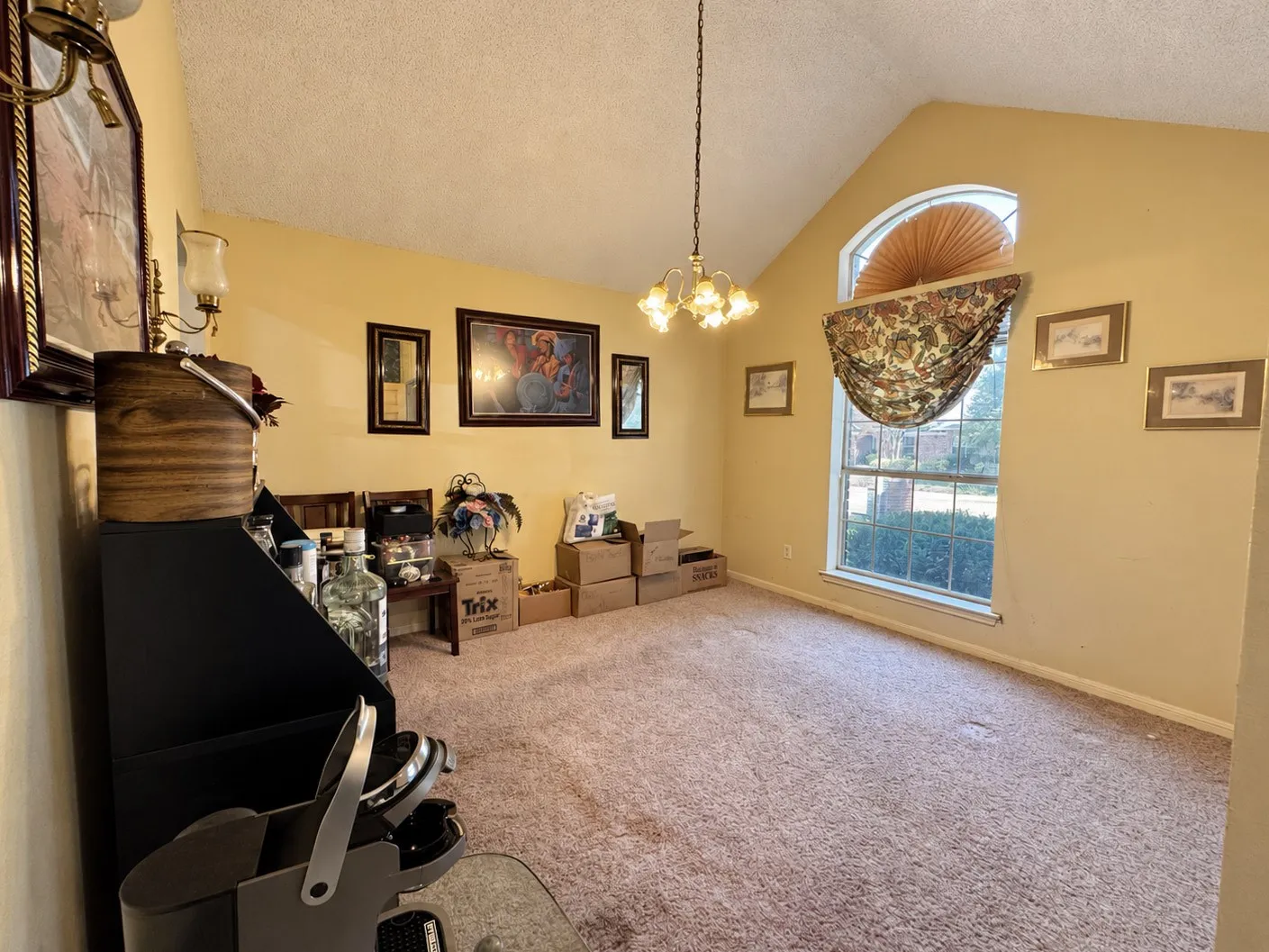 Vaulted ceiling with an arched window, central chandelier, and wall-mounted sconce