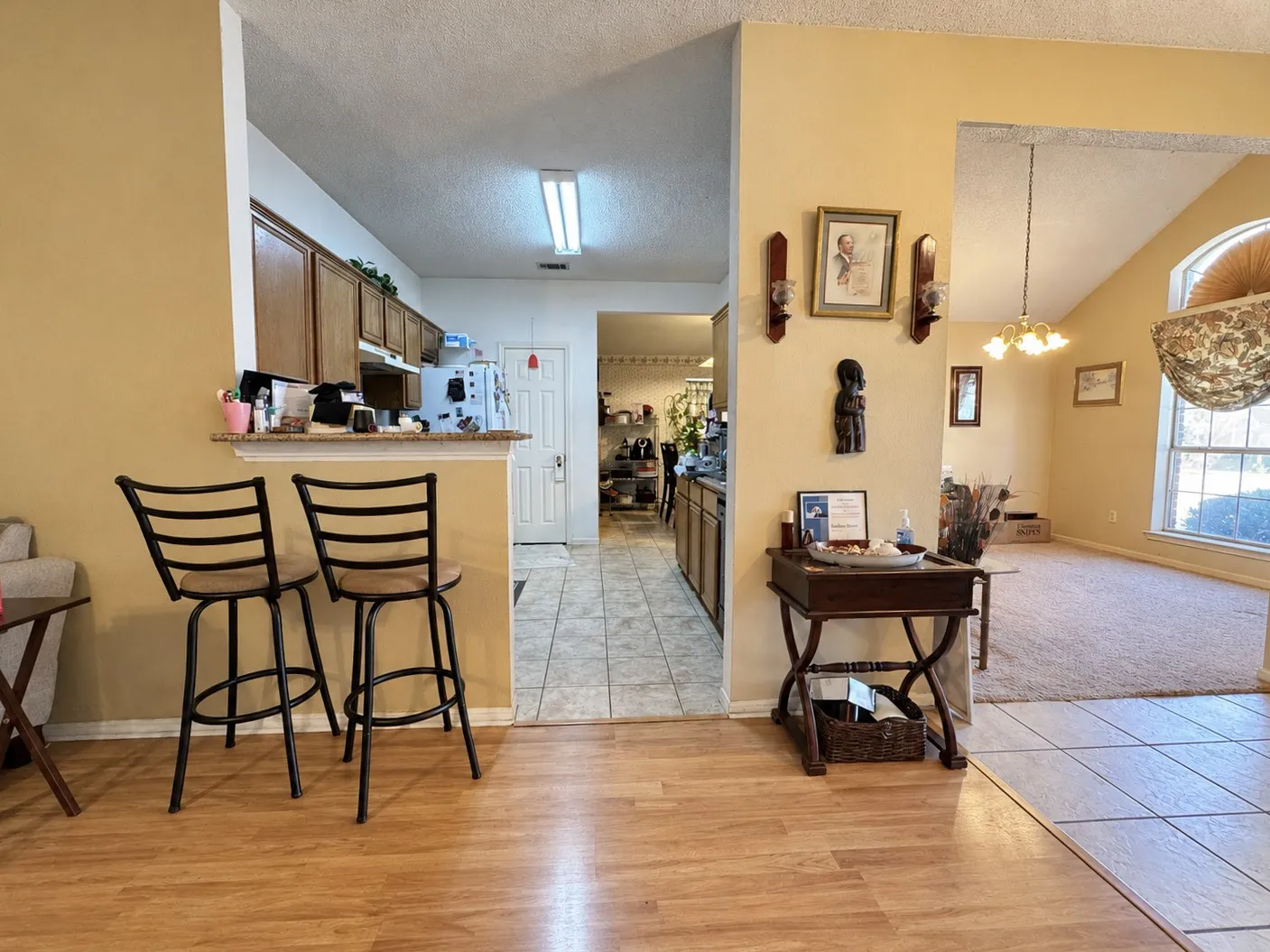 Kitchen pass-through with wood-finish flooring, tile flooring, and wood cabinetry