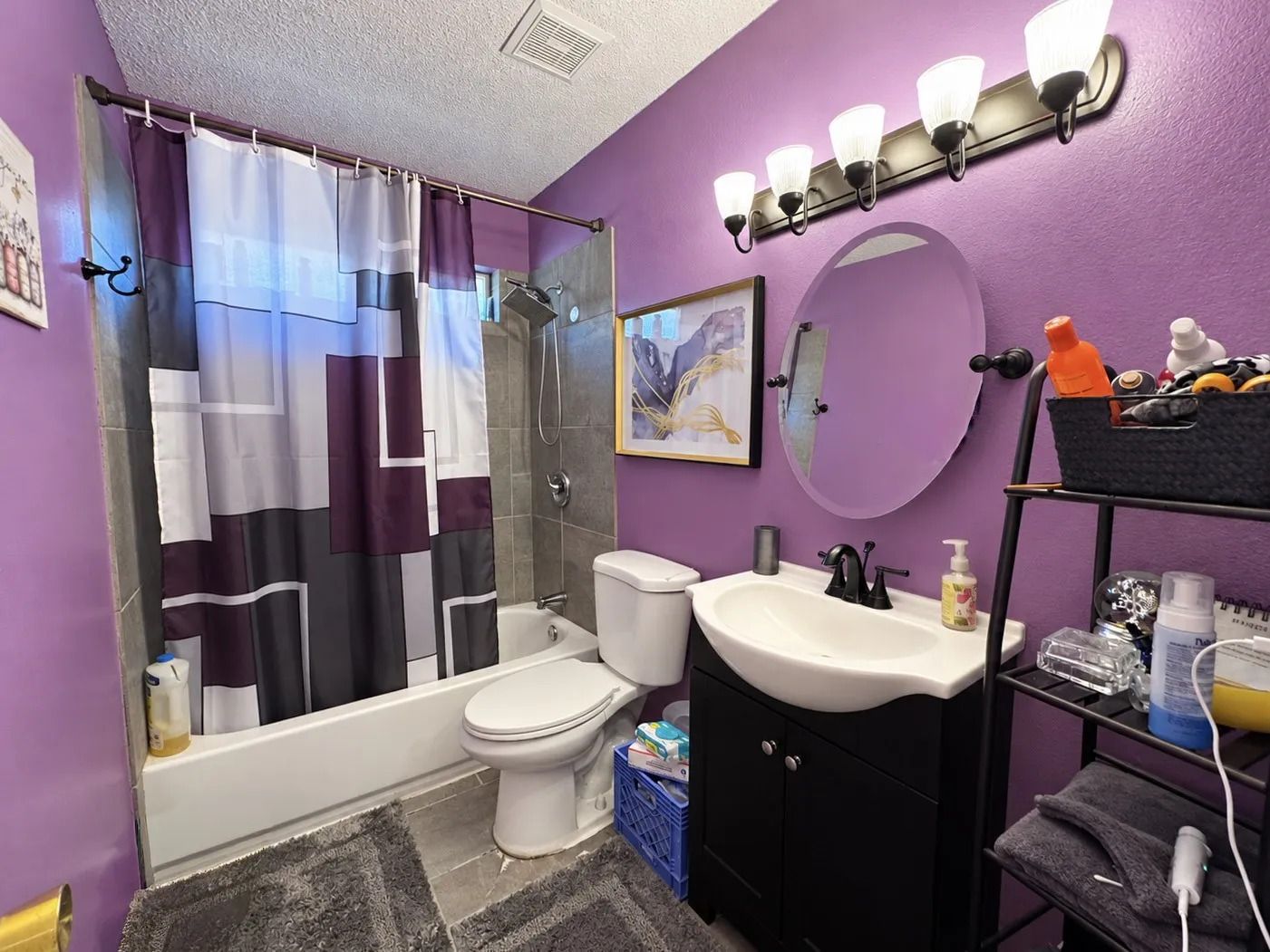 Bathtub with tile surround, a built-in toilet, and a vanity with an integrated sink and black faucet