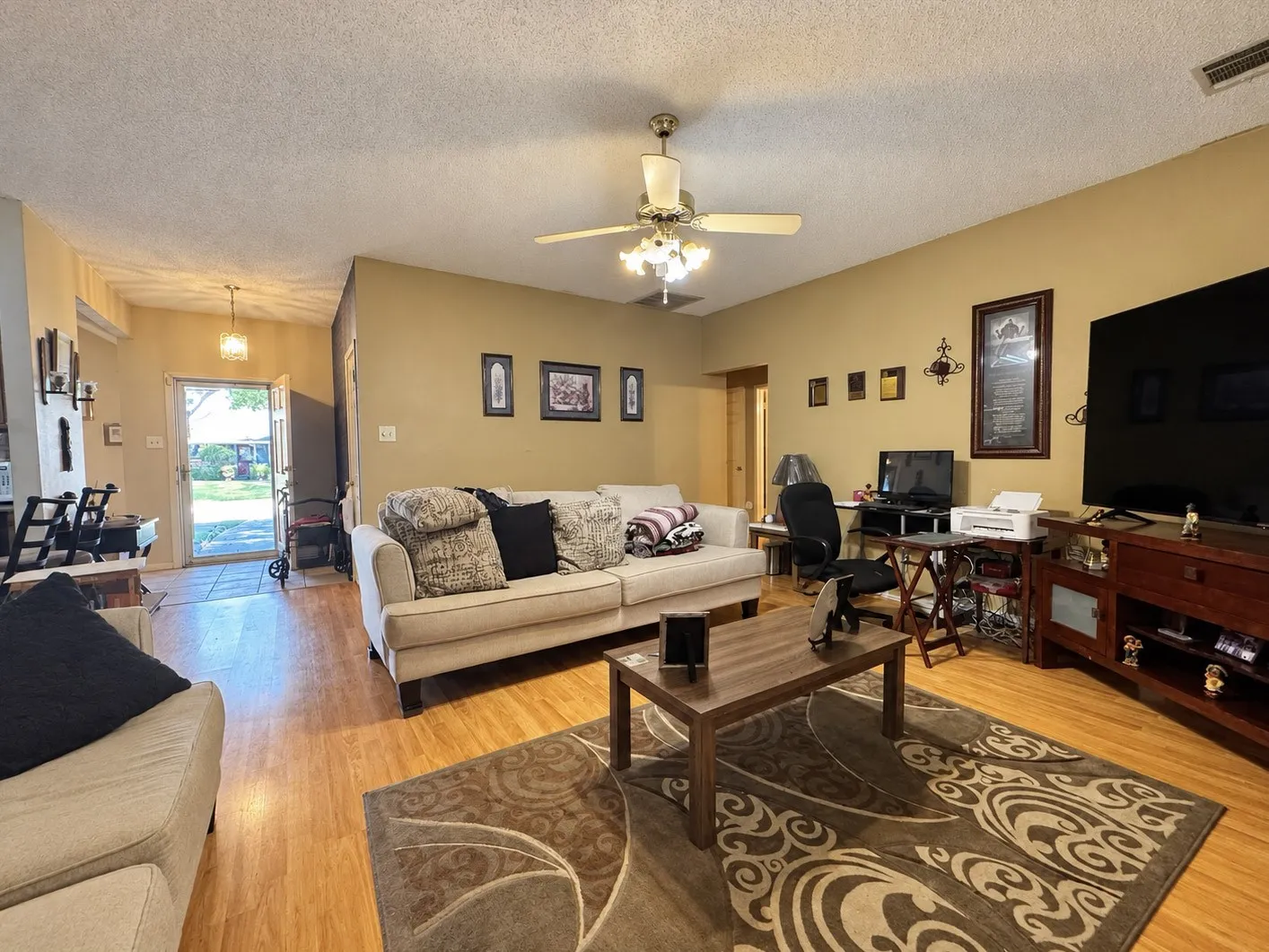 Wood-finish flooring throughout, ceiling fan with integrated lighting, and neutral wall tones