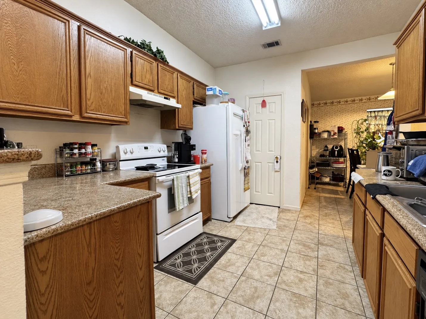 Kitchen featuring ample wood cabinetry, speckled countertops, a white electric range, a white refrigerator, and tile flooring