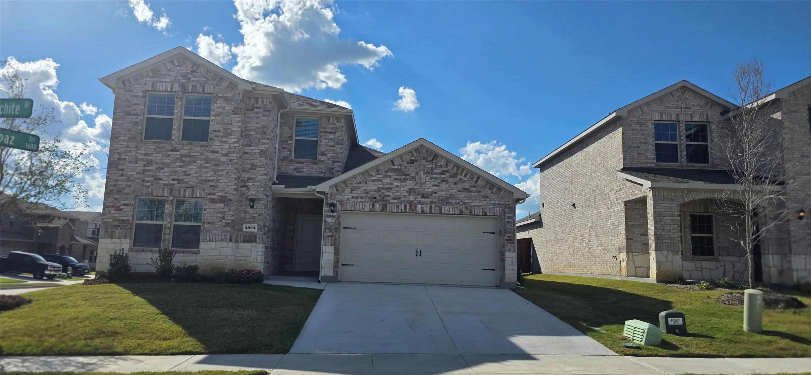 Two-story exterior with brick and stone accents, attached garage, and well-maintained front lawn
