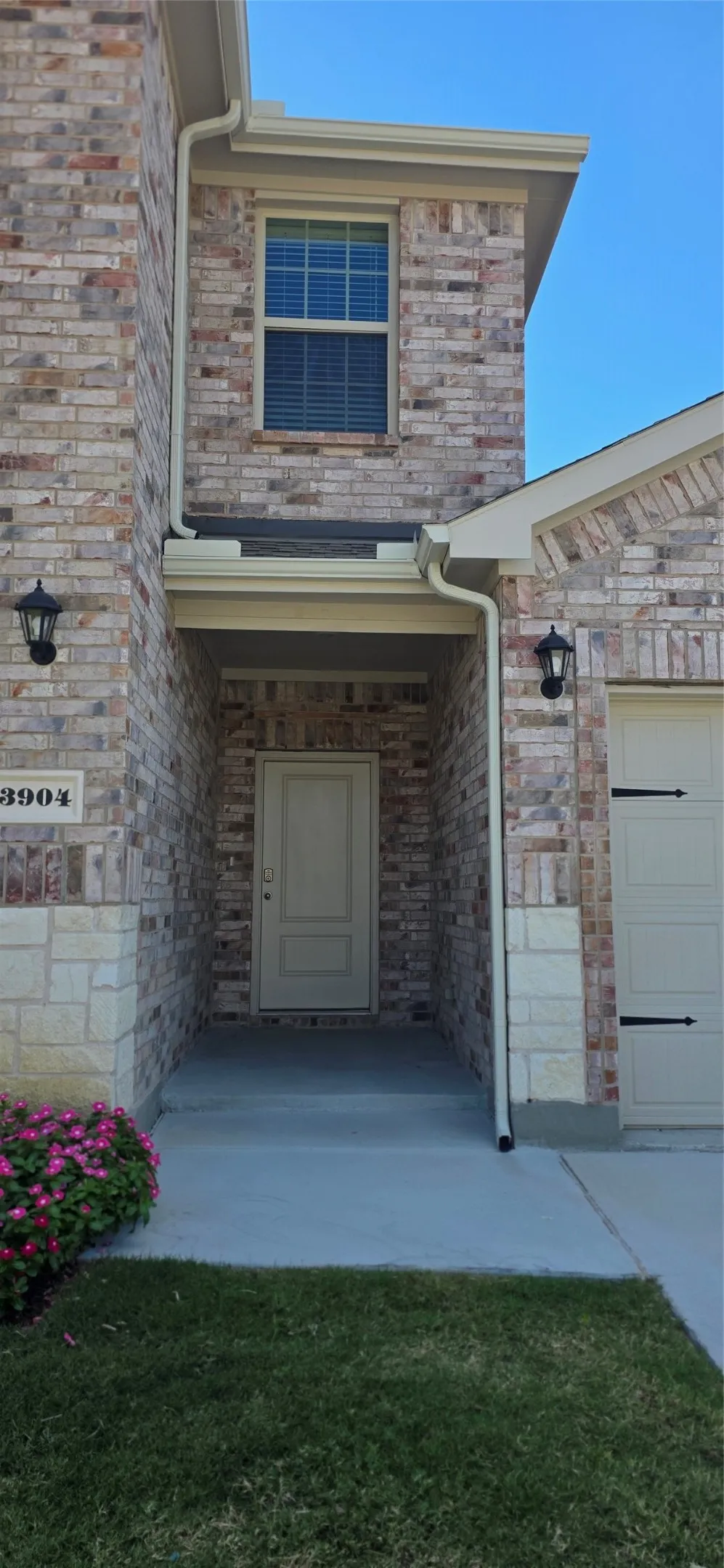 Brick and stone exterior with a recessed entry, covered porch, and integrated garage