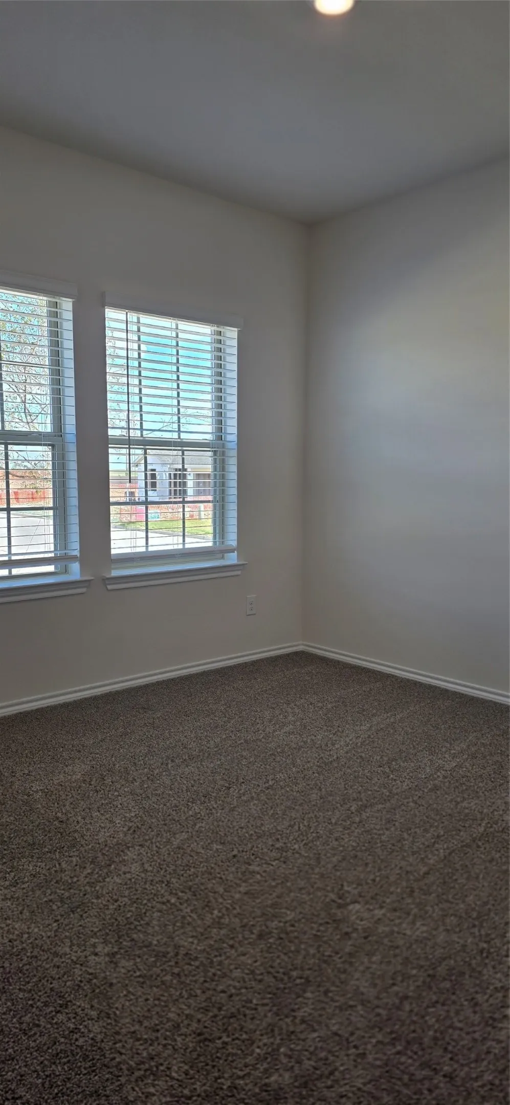 Two windows with blinds, recessed ceiling light, wall-to-wall carpeting, and light-toned wall finishes