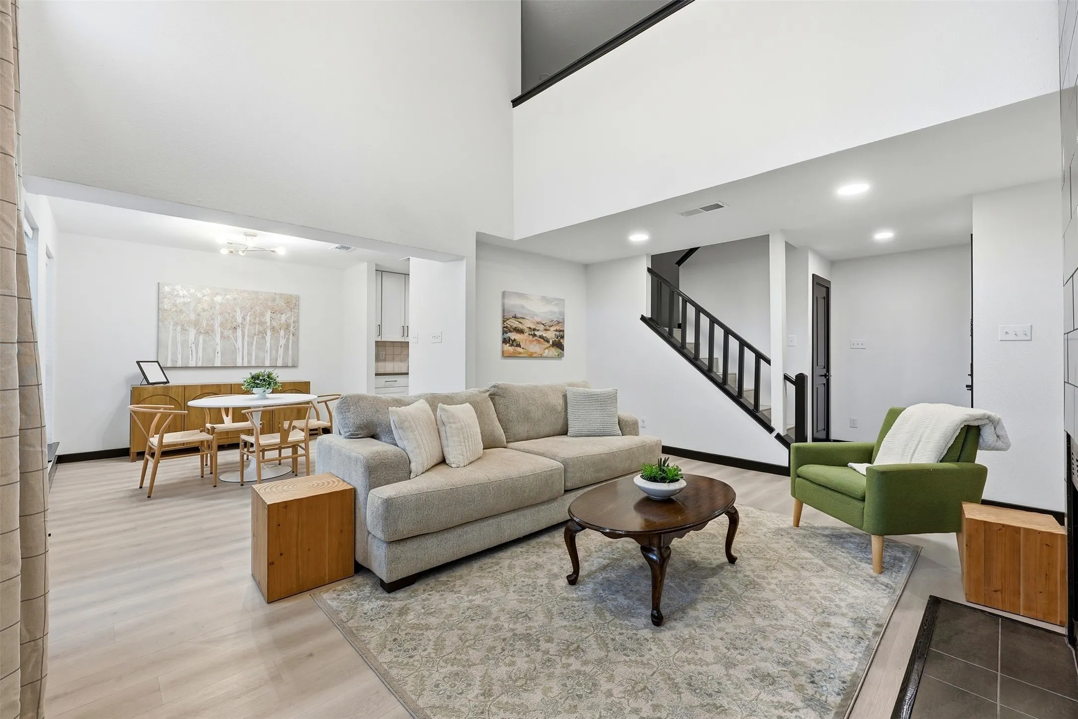Expansive living area featuring high ceilings, wood-finish flooring, and a staircase with dark wood railings