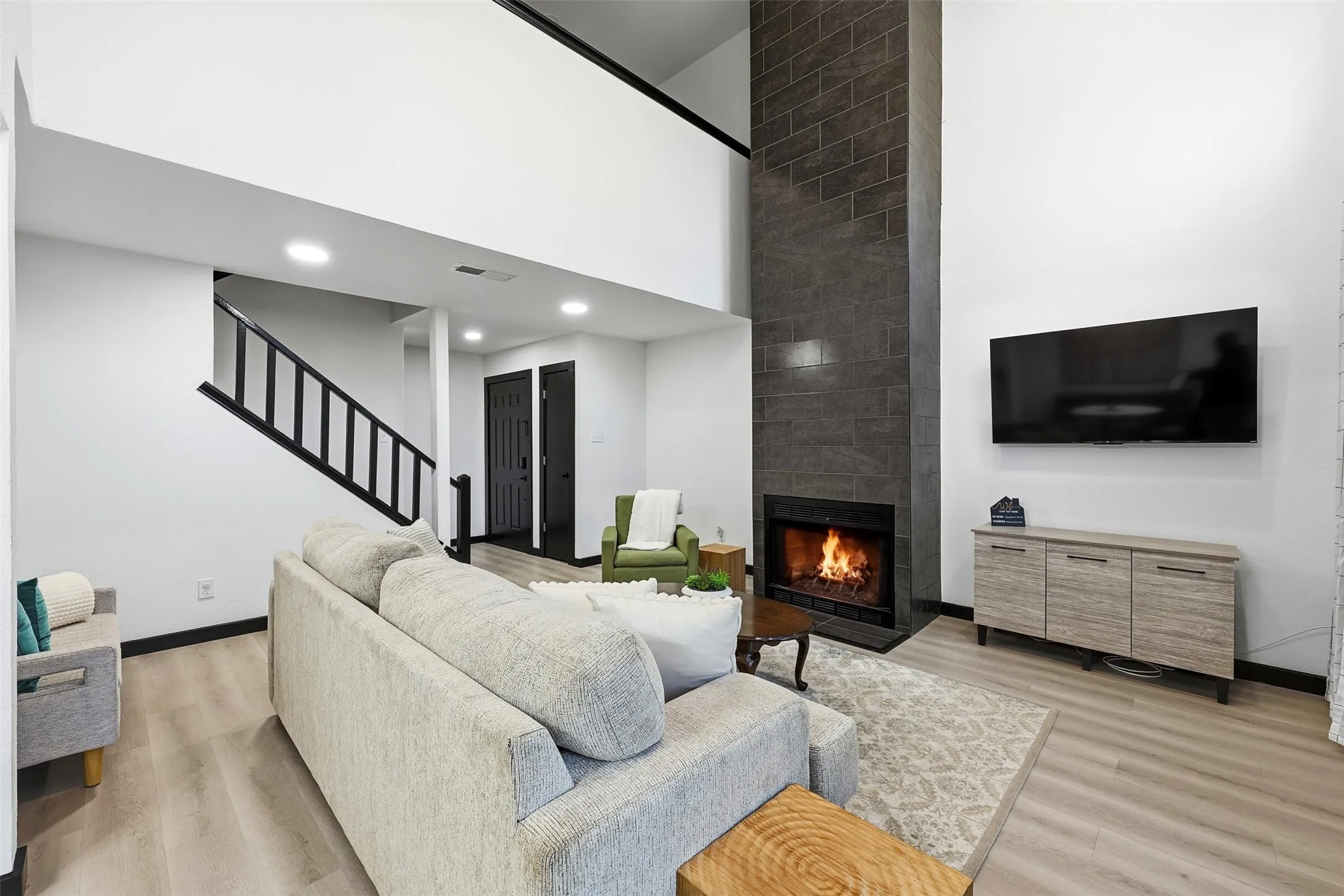 Two-story living area with a dark tile fireplace and light wood-finish flooring