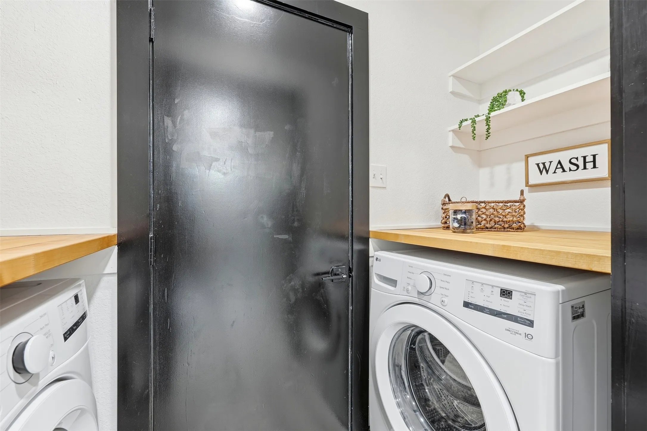 Built-in wood-finish countertop, front-load washing machine, and two floating shelves