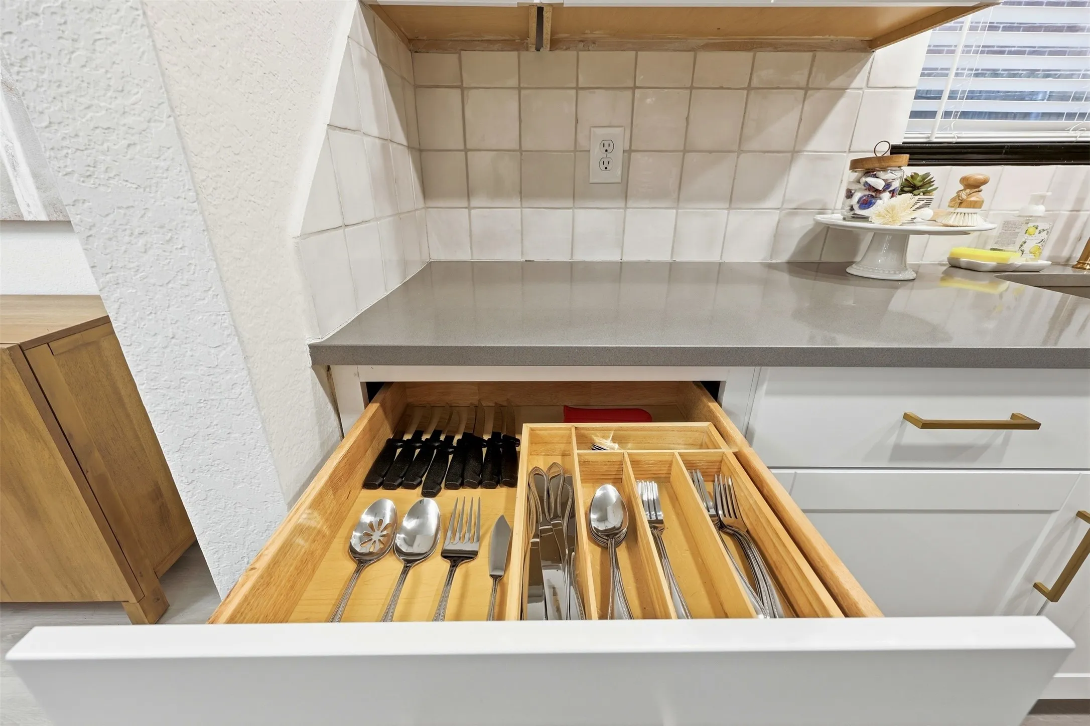White cabinetry with brass hardware, light gray countertop, and white tile backsplash