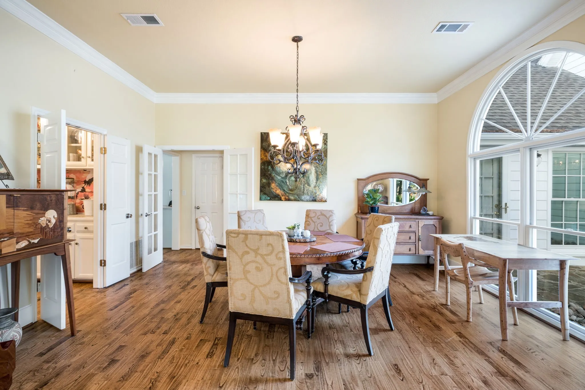 Hardwood-finish flooring, crown molding, French doors, and an arched window with transom detail