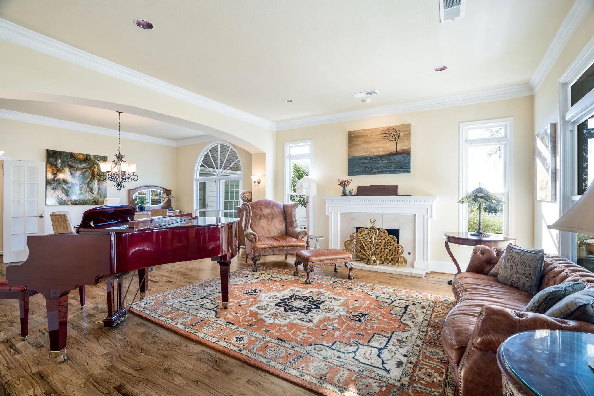 Hardwood flooring, crown molding, a built-in fireplace with a decorative screen, recessed lighting, and arched doorways