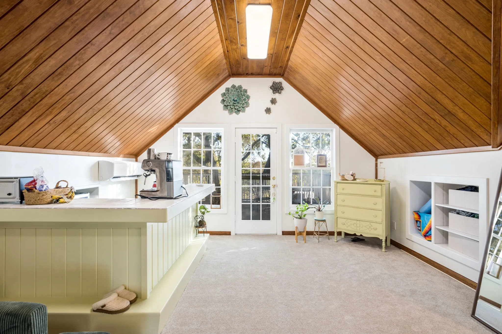 Vaulted wood-paneled ceiling, built-in shelving, white paneled wall accents, white French doors, and a built-in counter