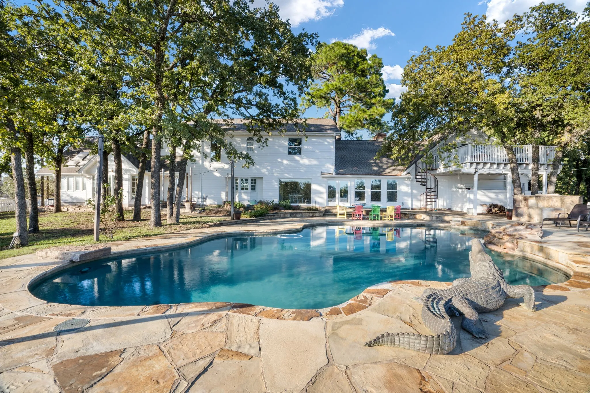 Curved swimming pool with an integrated spa, surrounded by natural flagstone coping and decking