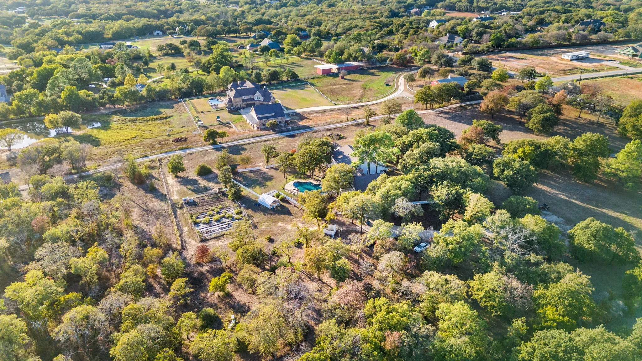 Expansive acreage featuring multiple structures, an outdoor swimming pool, and mature trees