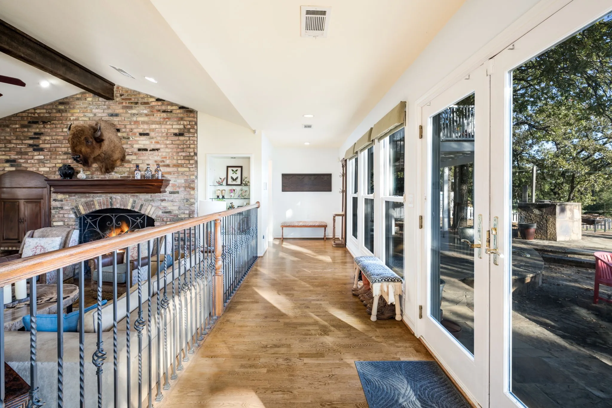 Hardwood flooring throughout, brick accent wall with a built-in fireplace, exposed wood beam, and multiple glass-paneled doors with direct outdoor access
