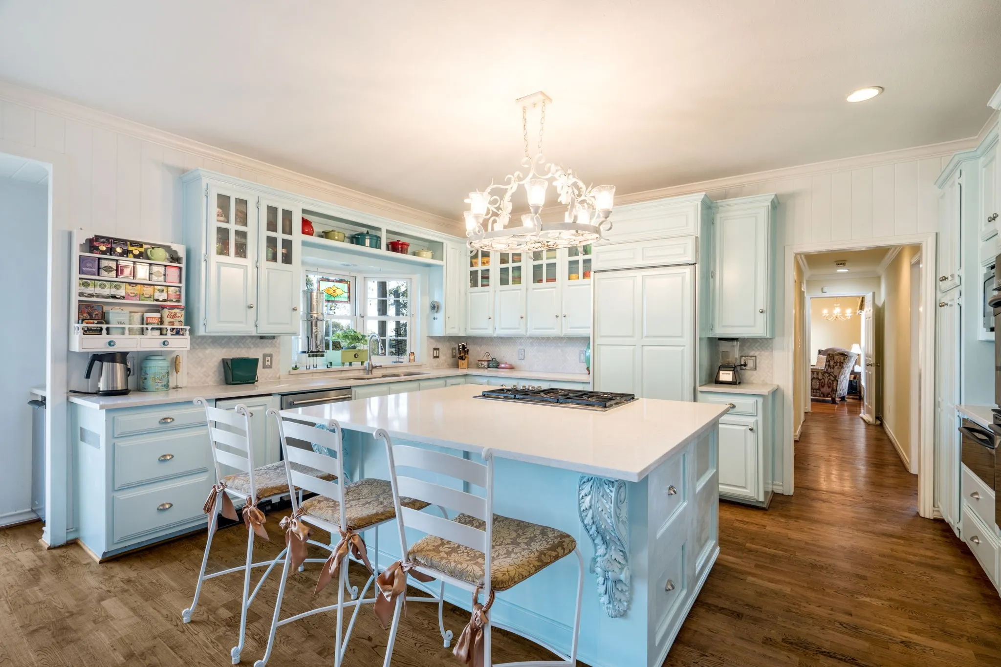 Wood-finish flooring with a light blue kitchen island featuring carved corbels