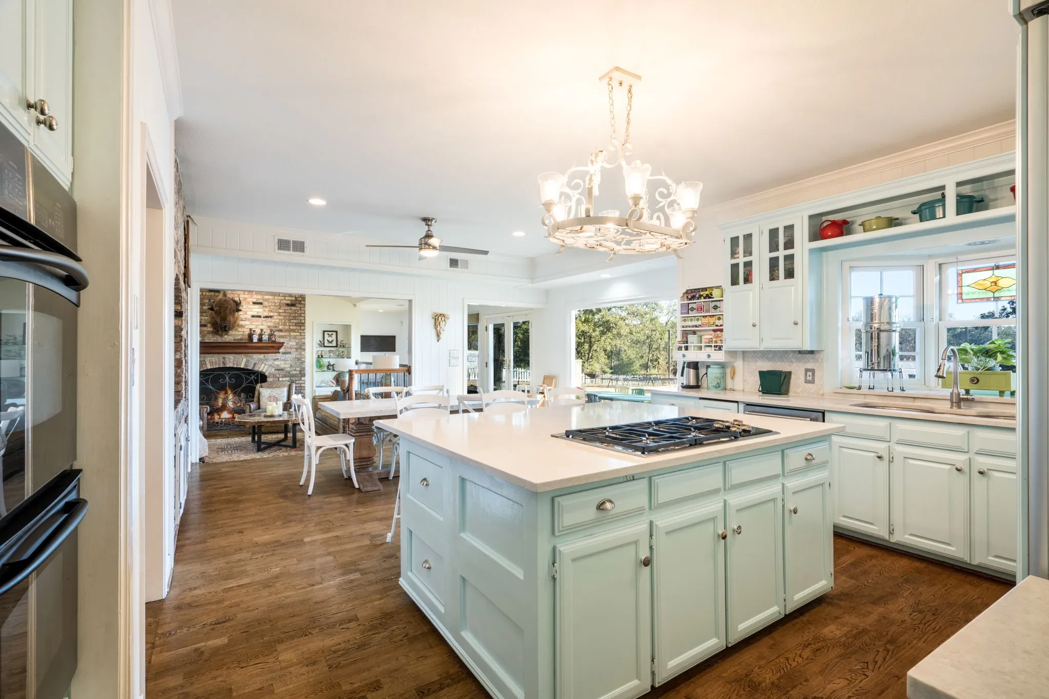 Kitchen featuring a central island with cooktop, light-toned cabinetry, light-toned countertops, and wood-finish flooring