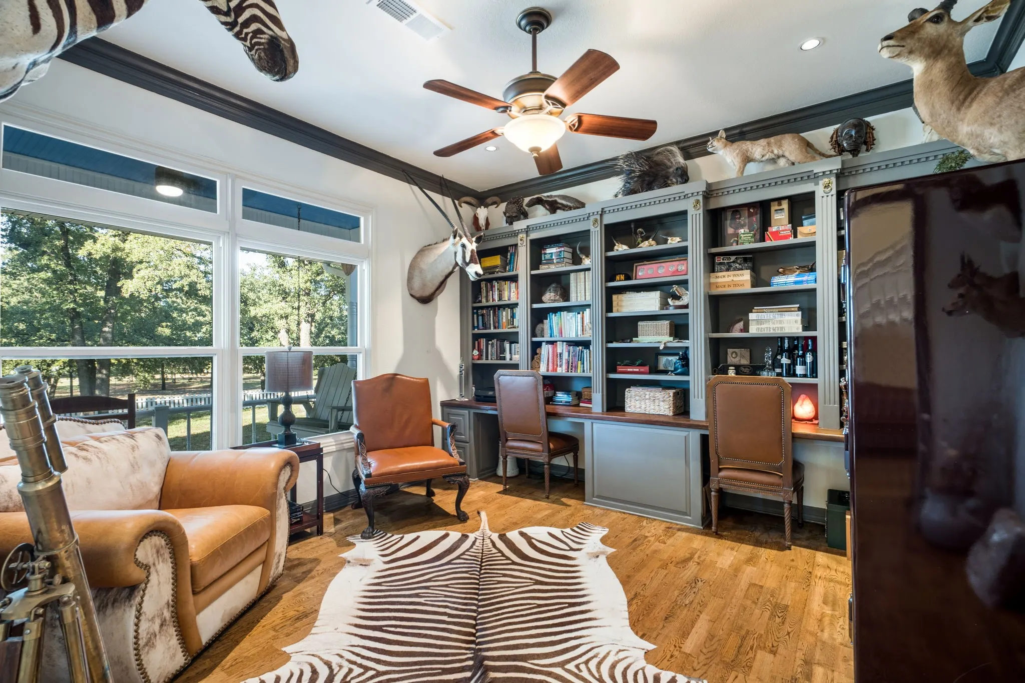 Hardwood-finish flooring, built-in shelving, ceiling fan with integrated lighting, recessed lighting, and large picture windows