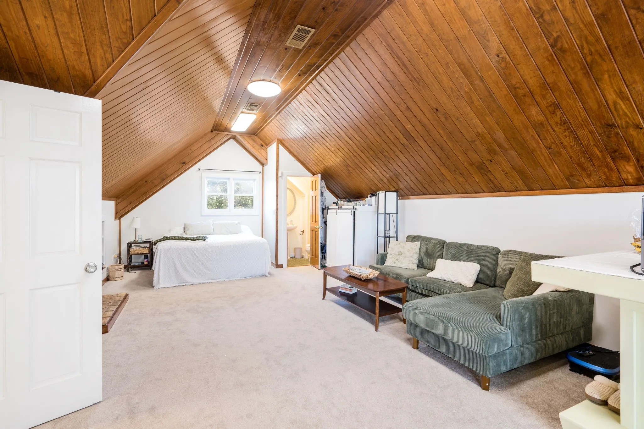 Wood-paneled vaulted ceiling, white walls, and light-colored carpeting