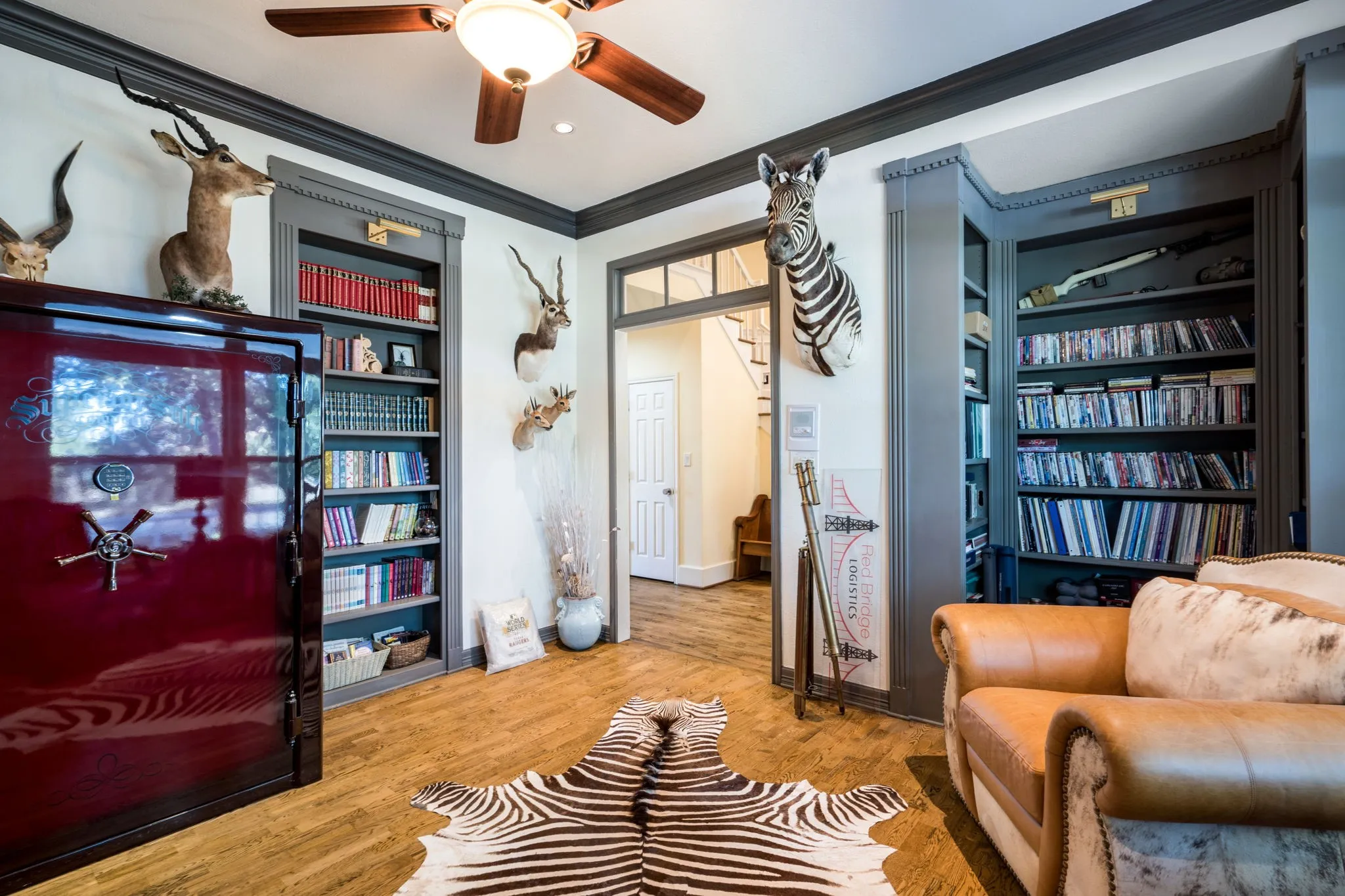 Wood-finish flooring, built-in shelving, crown molding, and a ceiling fan with integrated lighting