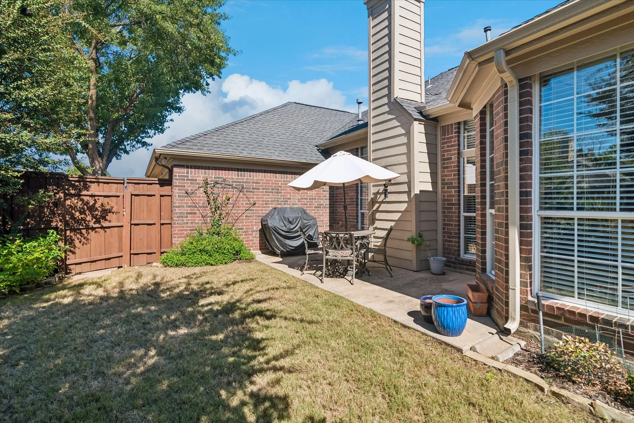 Private outdoor patio with a concrete slab, brick exterior, and wood fencing