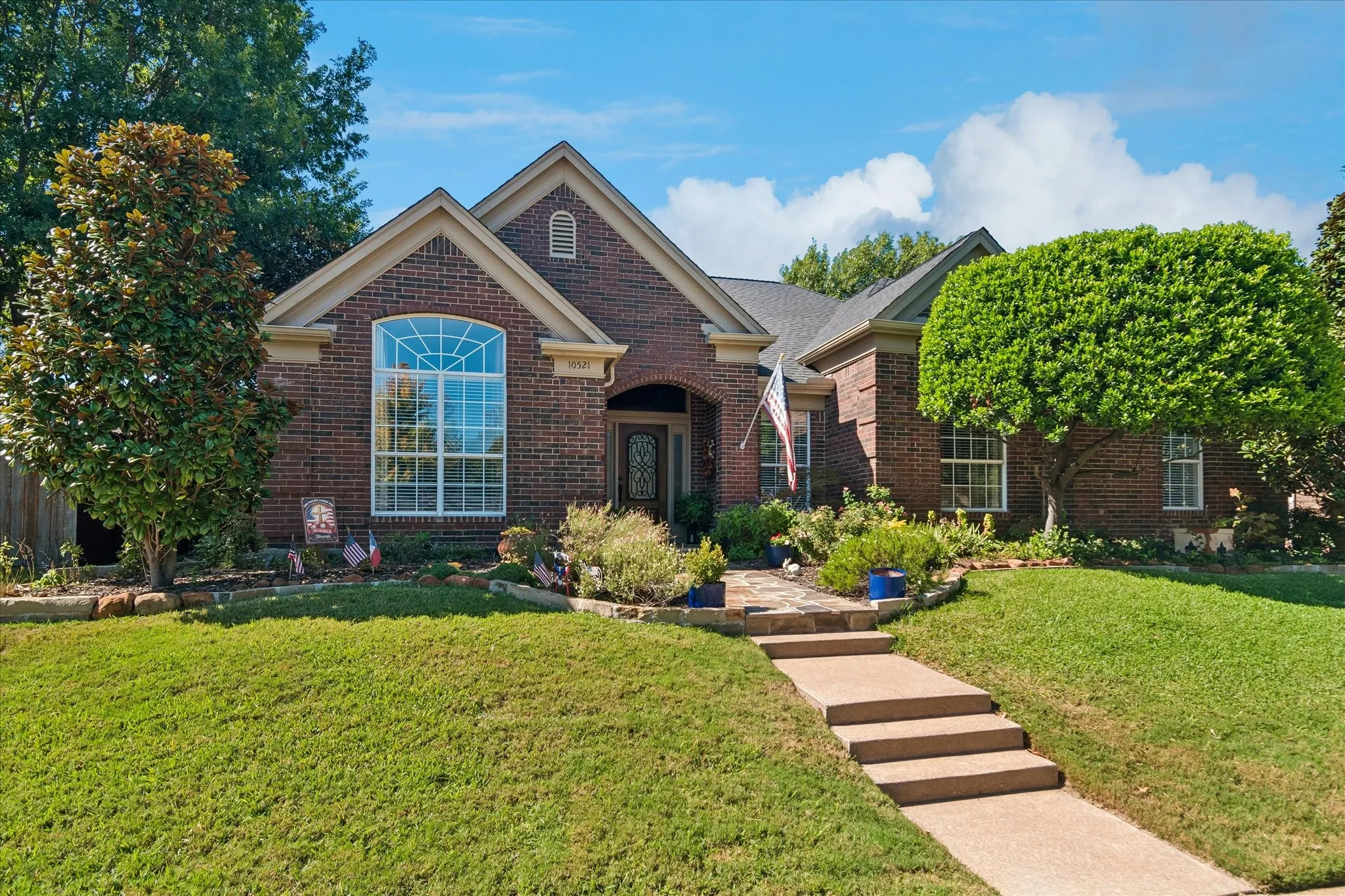 Brick exterior with gabled roof lines, featuring a large arched window and a covered entry