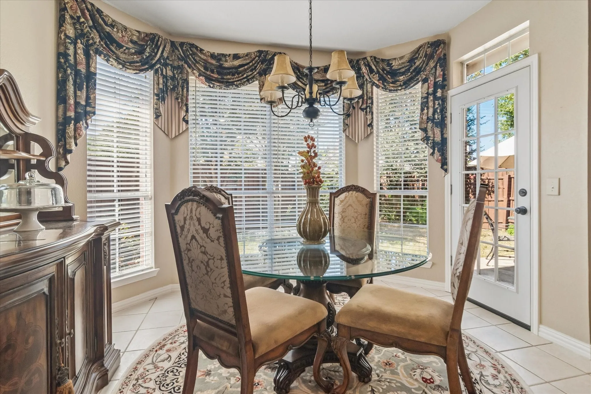 Bay window with horizontal blinds, tiled flooring, built-in buffet, and a paneled glass-insert door