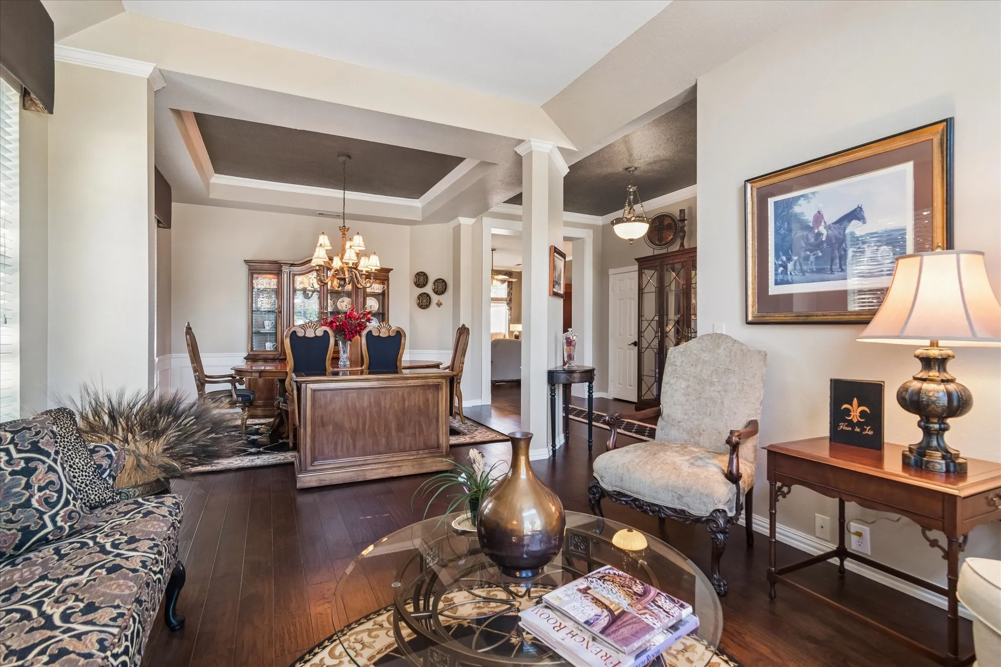 Hardwood-finish flooring, recessed tray ceiling, crown molding, and wainscoting details create a refined interior