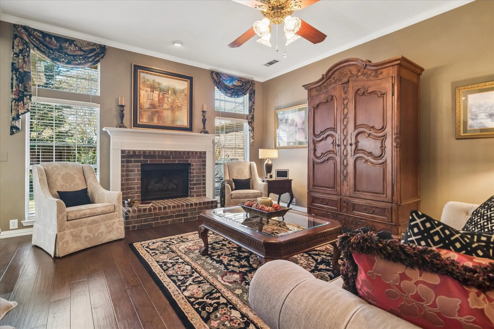 Warm wood-finish flooring complemented by a brick-surround fireplace with a white mantel