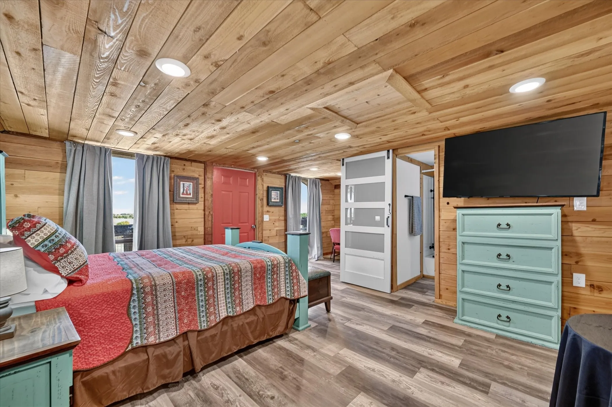 Wood-finish flooring, wood-paneled walls, wood-paneled ceiling, recessed lighting, and a sliding barn door with frosted glass panels