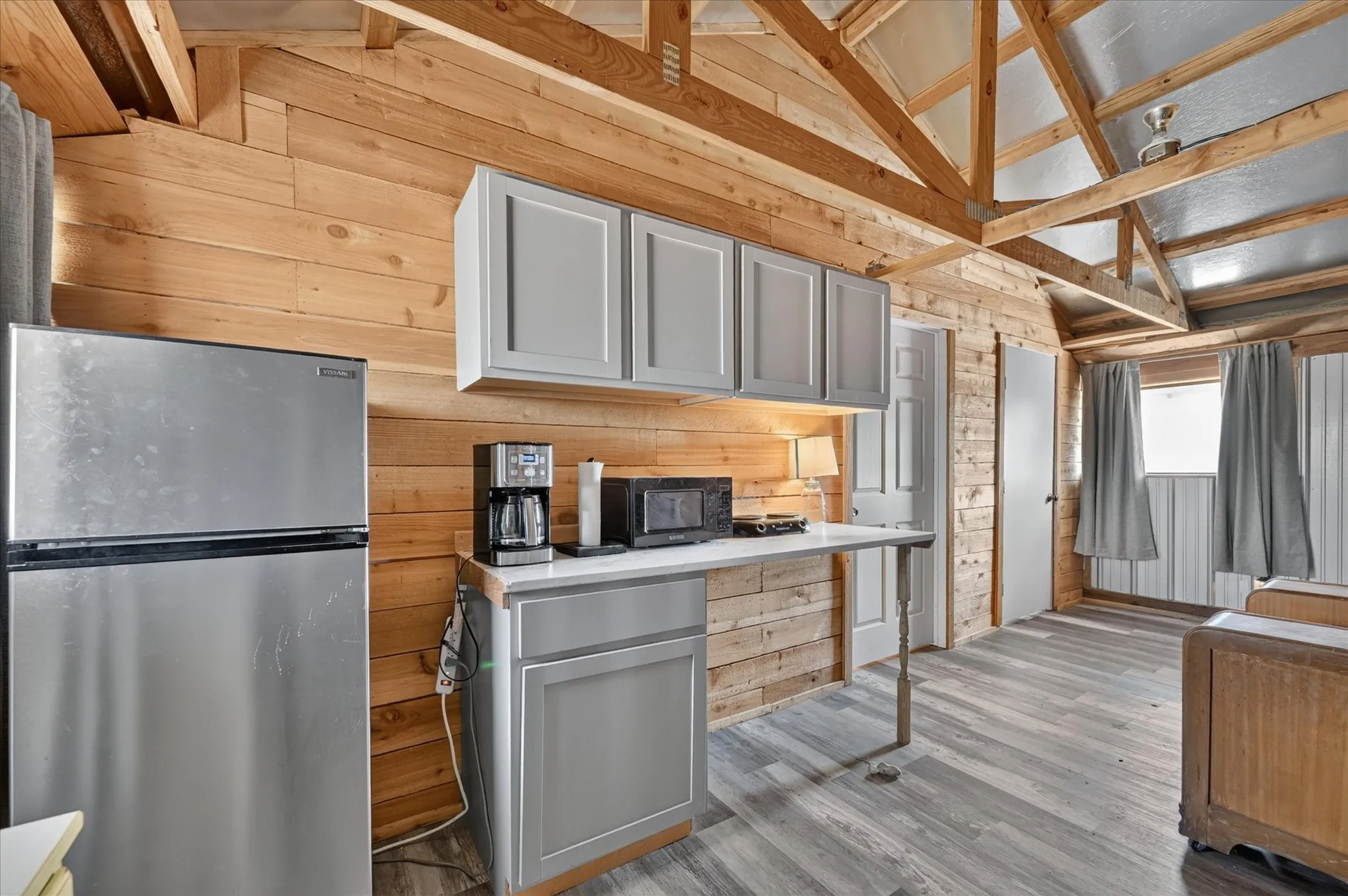 Wood-paneled walls and ceiling beams complement the gray cabinetry and wood-finish flooring