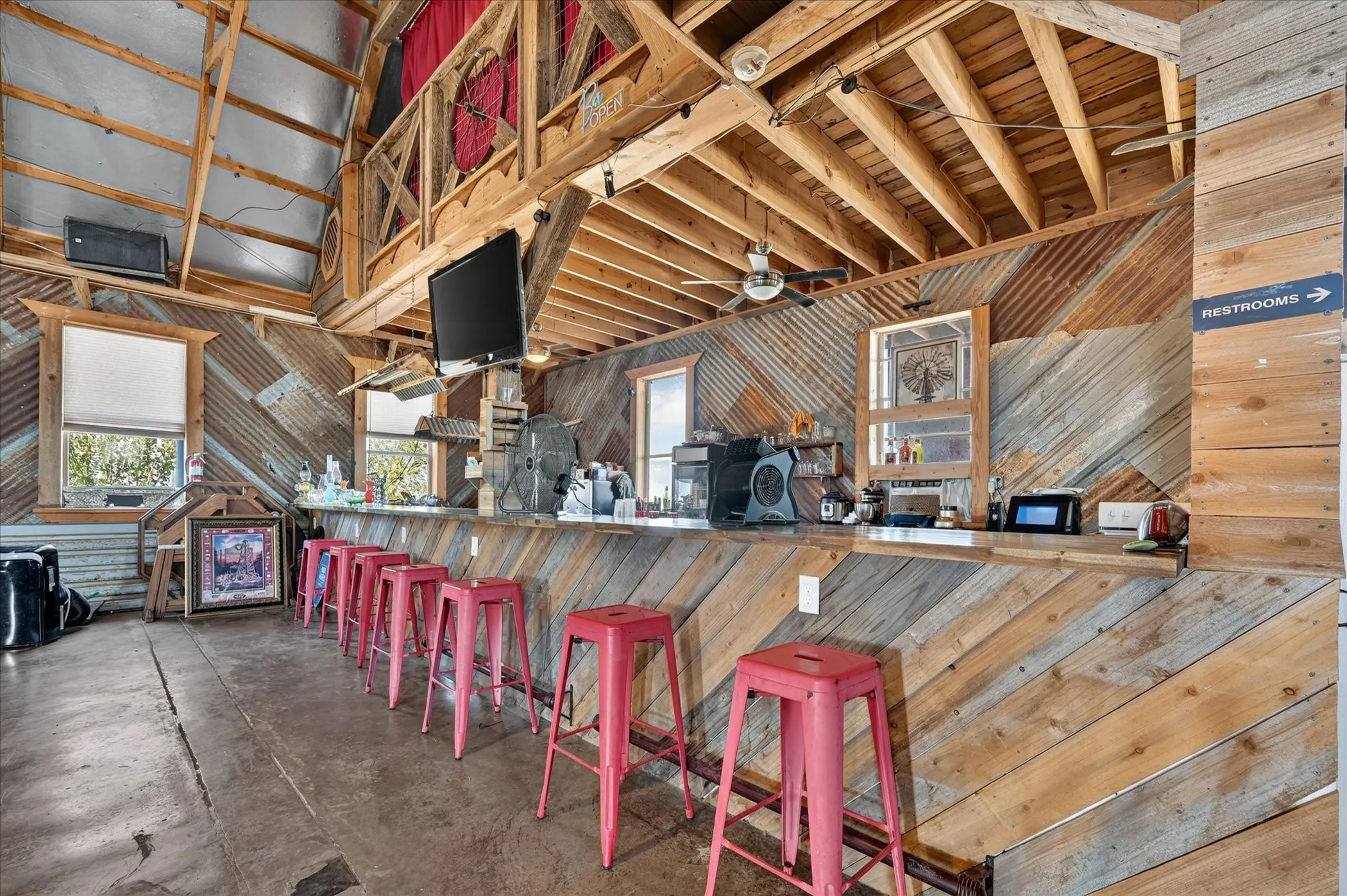 Open-concept space featuring exposed wood beam ceilings and a high-top bar with a wood-finish countertop