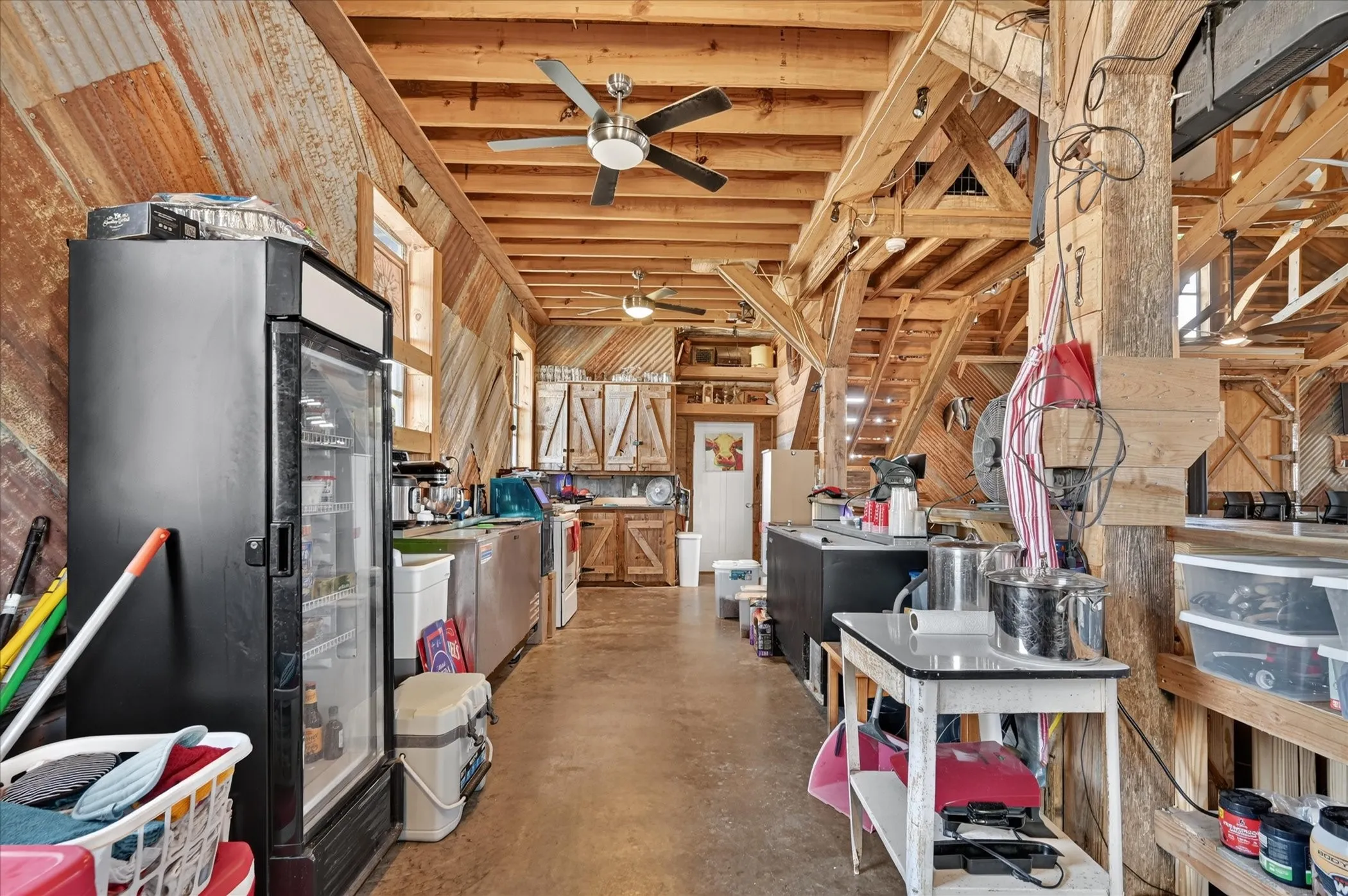 Exposed wood beam ceiling, wood-finish wall paneling, ceiling fans, built-in wooden cabinetry, and durable flooring