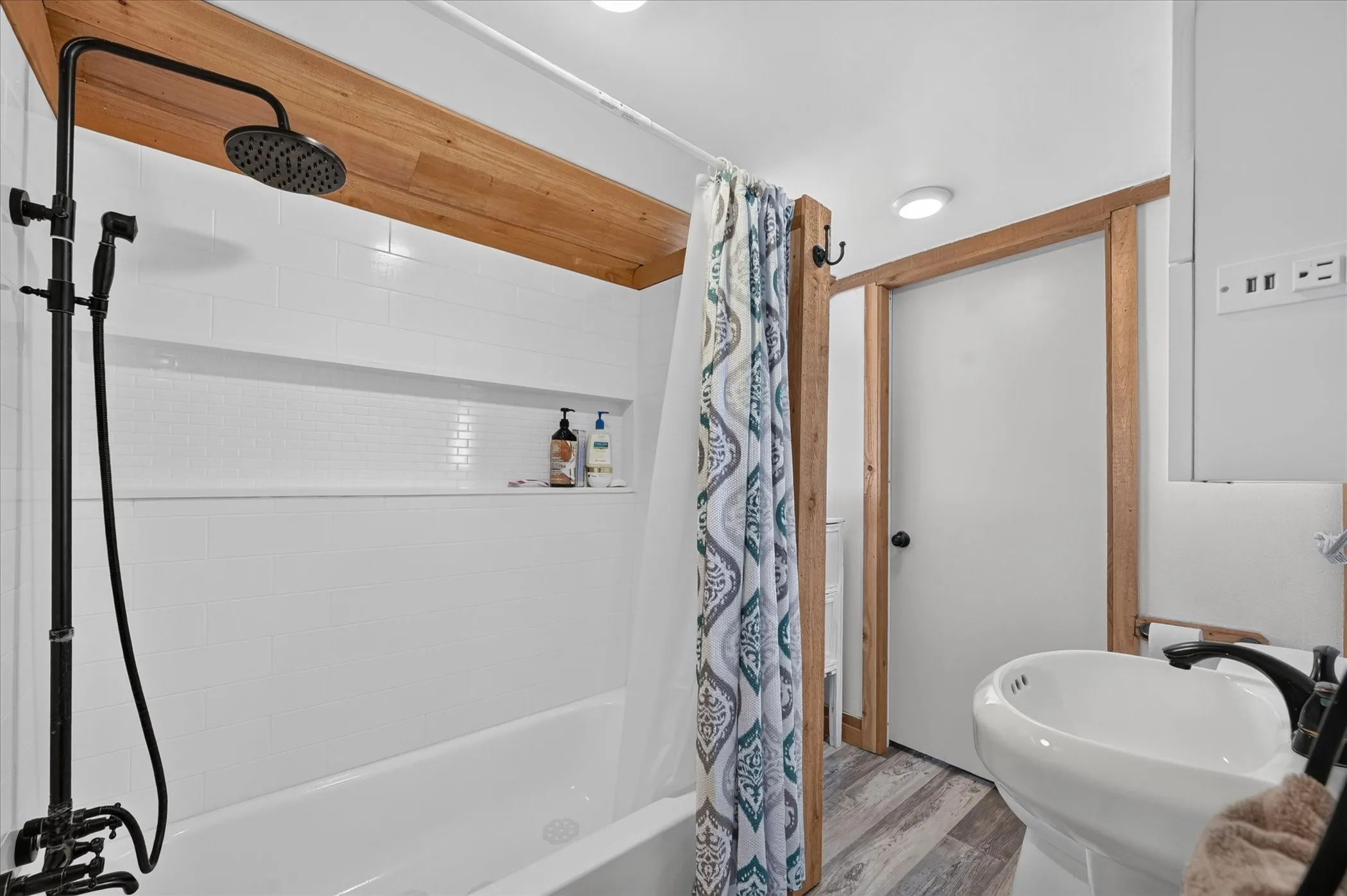 Bathtub with white subway tile surround, built-in tile niche, and matte black shower fixtures