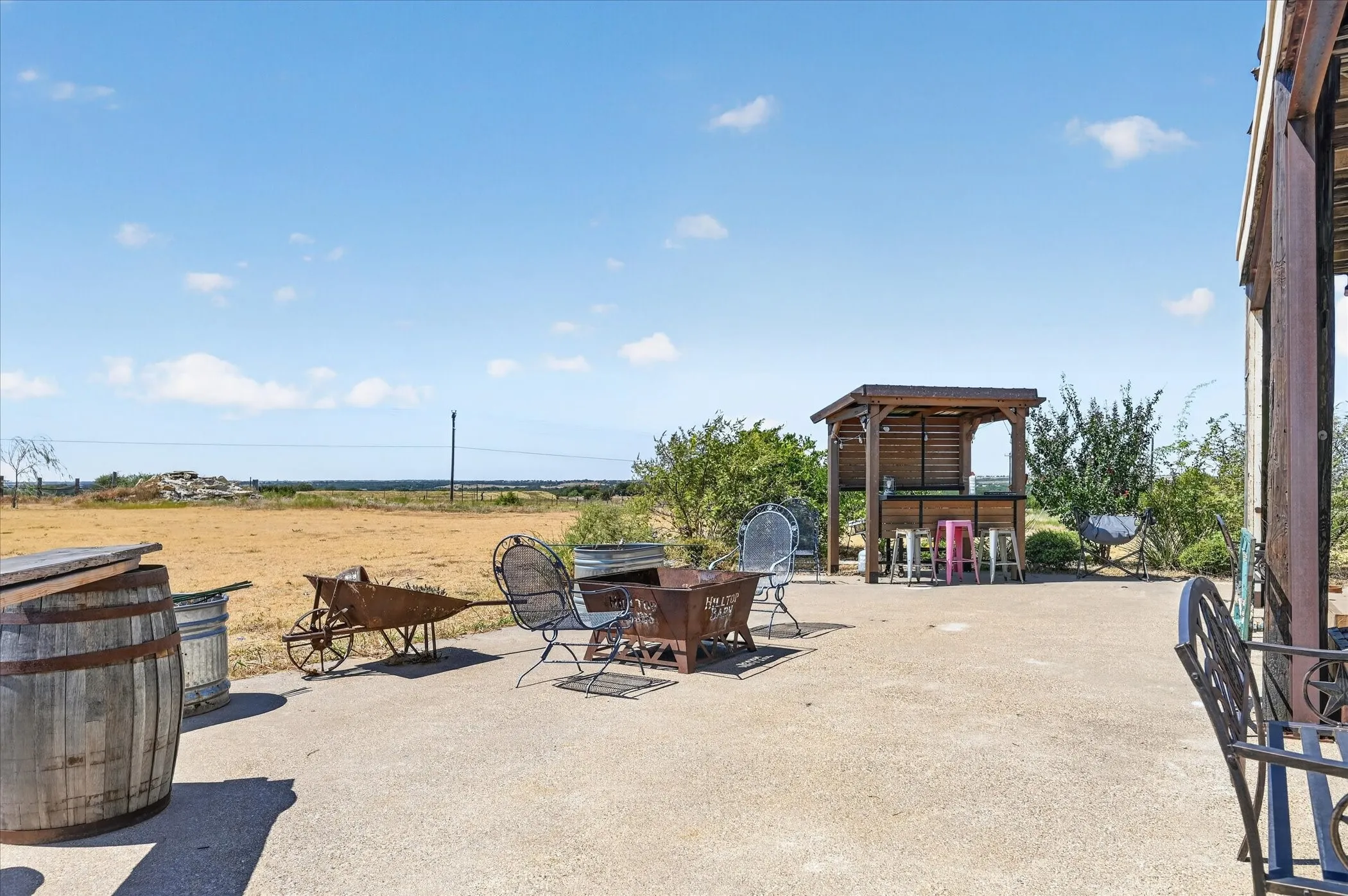 Expansive concrete patio featuring a built-in outdoor bar with a wooden pergola