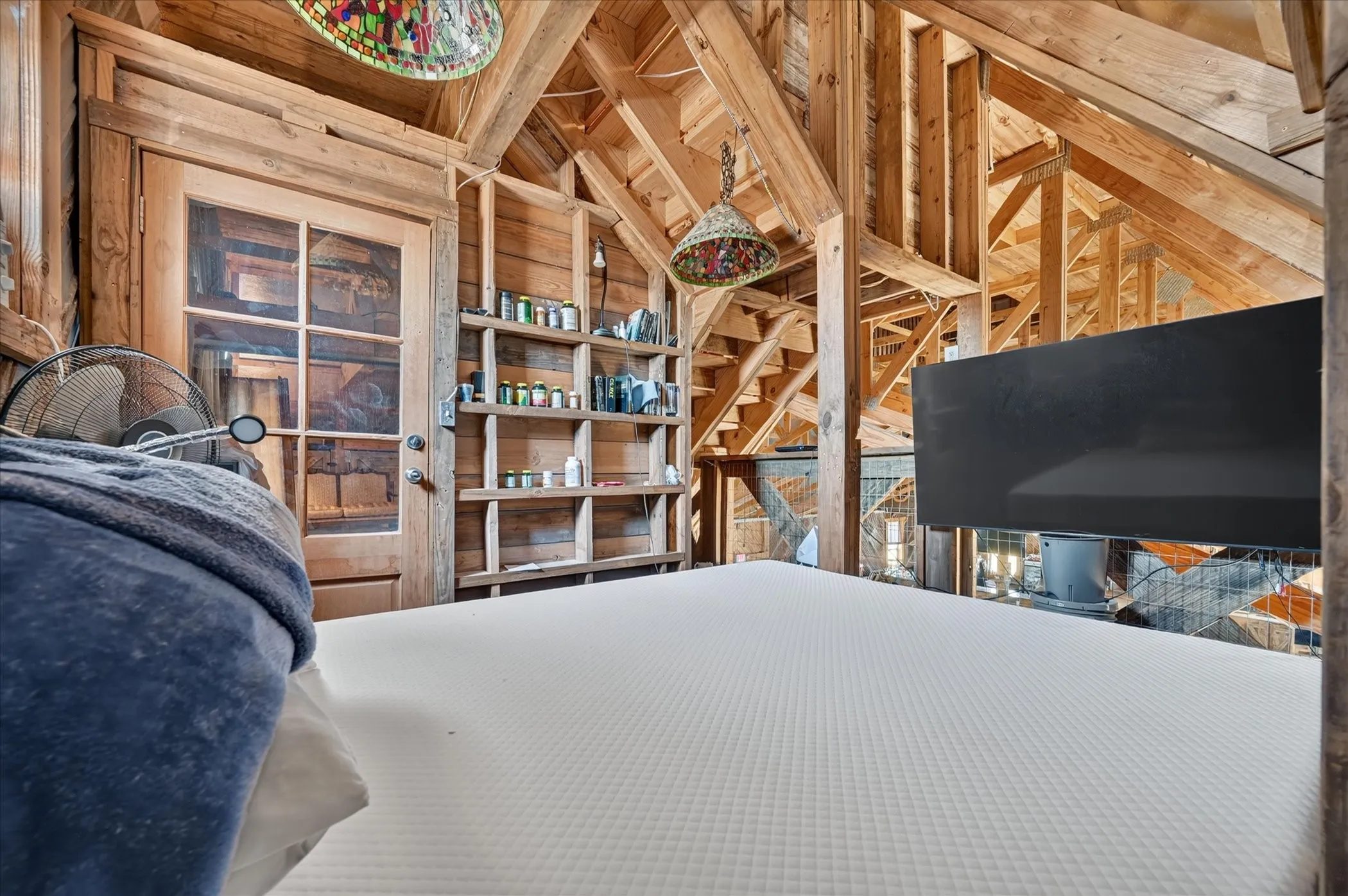 Exposed timber framing, wood-clad walls, built-in shelving, and a wood-frame glass panel door