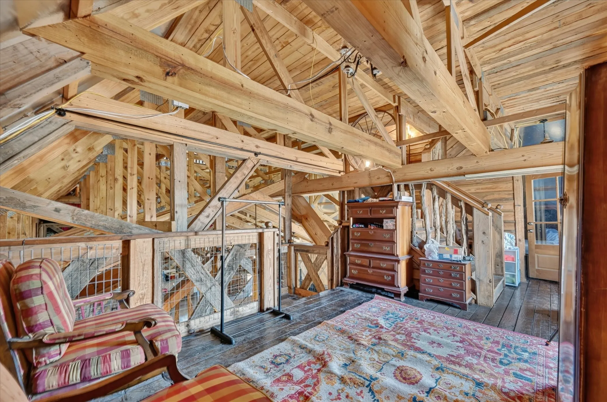 Vaulted wood ceilings with exposed beams, wood-finish flooring, and a wood railing with metal grates