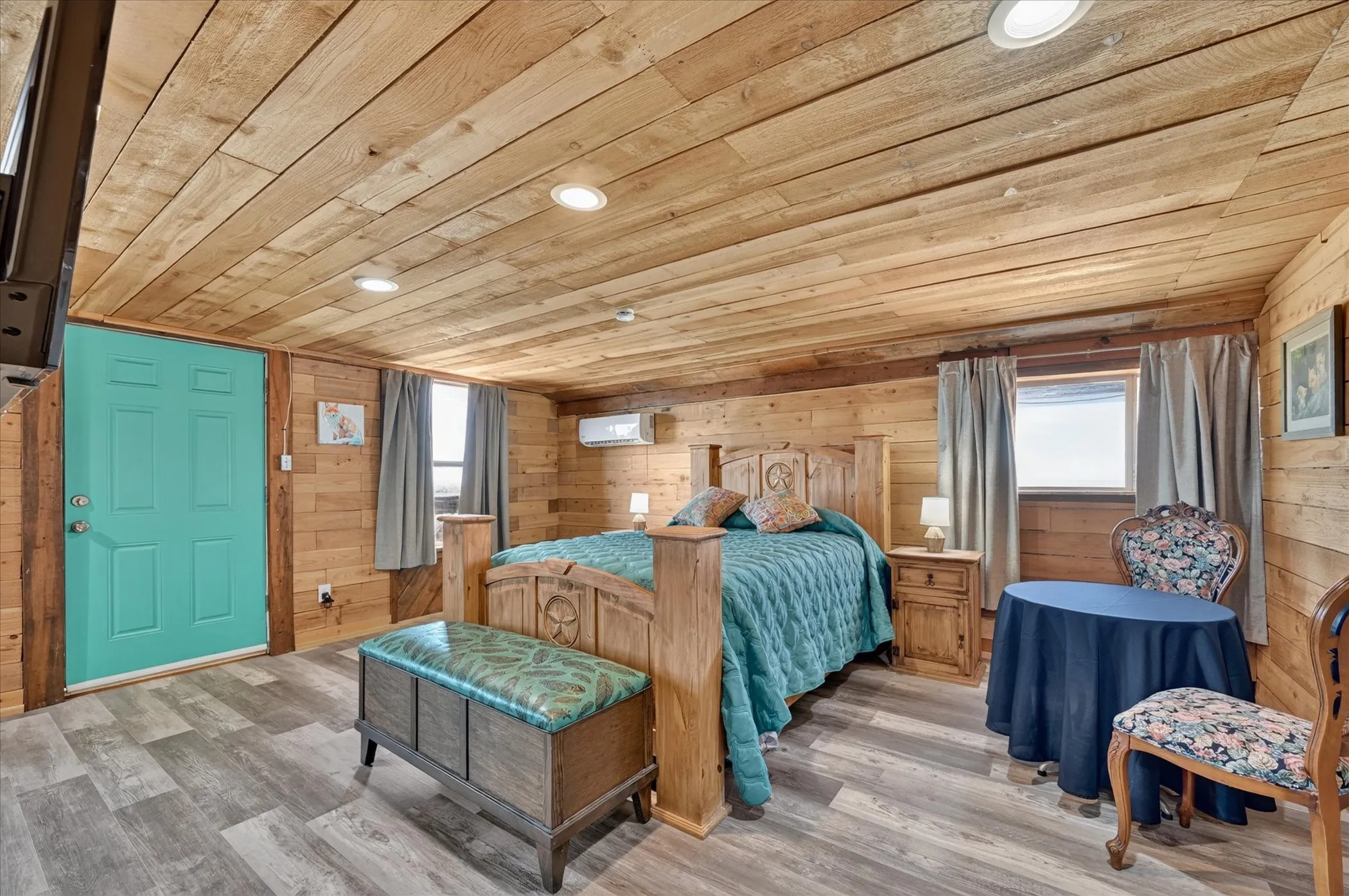 Wood-paneled walls and ceiling, recessed lighting, wood-finish flooring, and a vibrant teal entry door