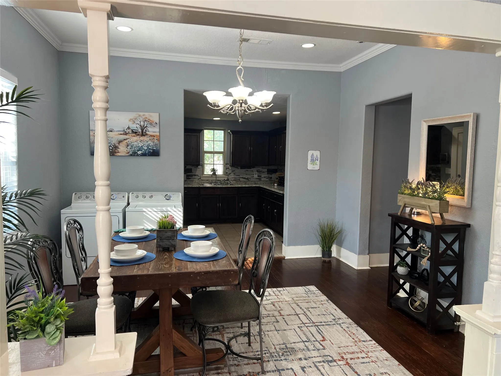 Hardwood flooring, crown molding, and a chandelier illuminate the space