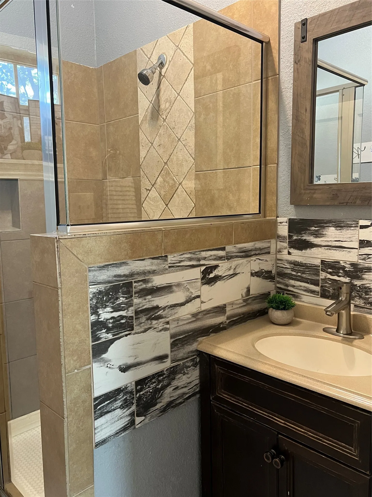 Glass-enclosed shower with tiled walls and a diagonal accent band