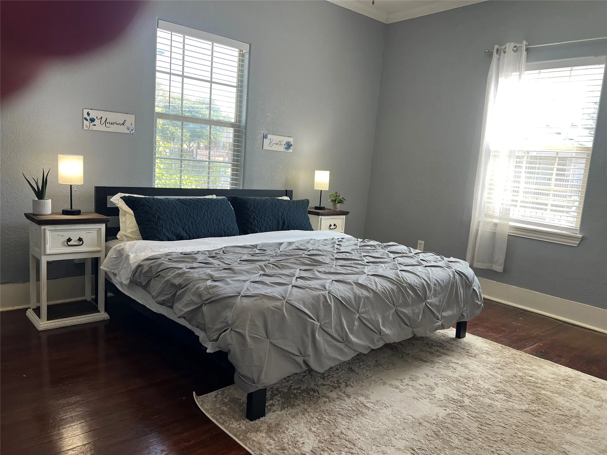 Rich wood-finish flooring with a light-toned area rug
