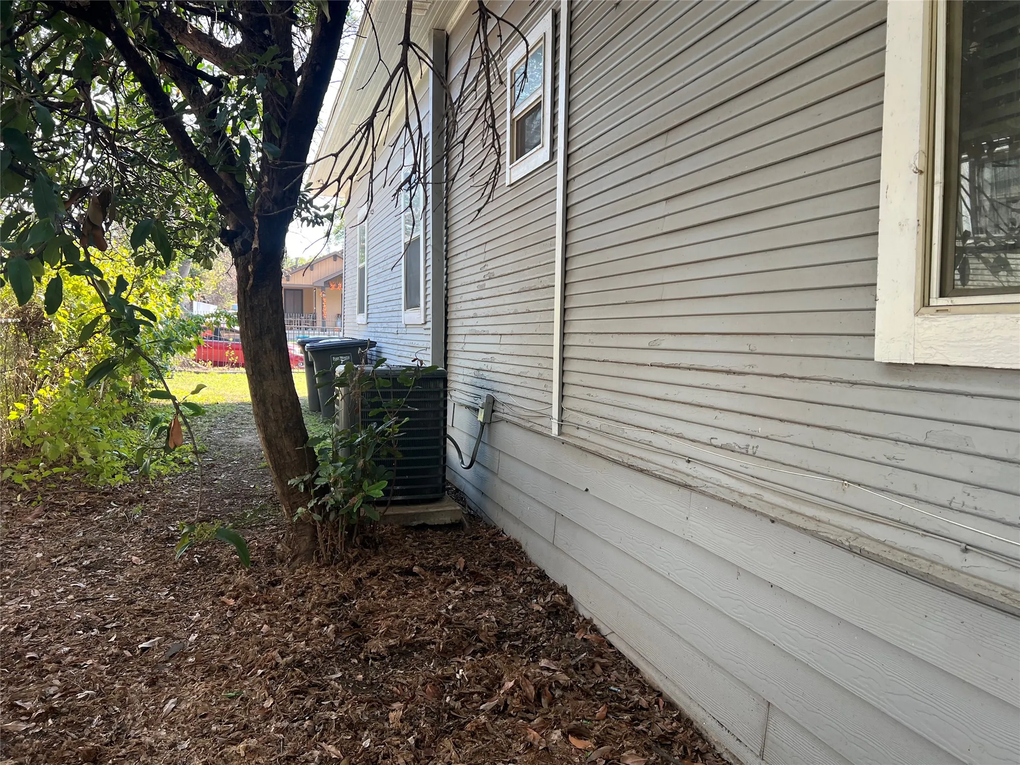 Exterior siding with horizontal panels, foundational skirting, and a visible air conditioning unit