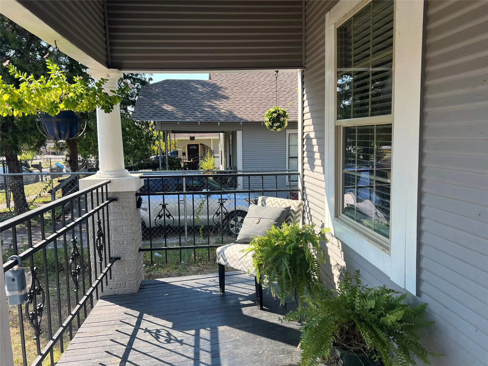 Front porch featuring a corrugated ceiling, decorative wrought iron railing, and a window with white trim