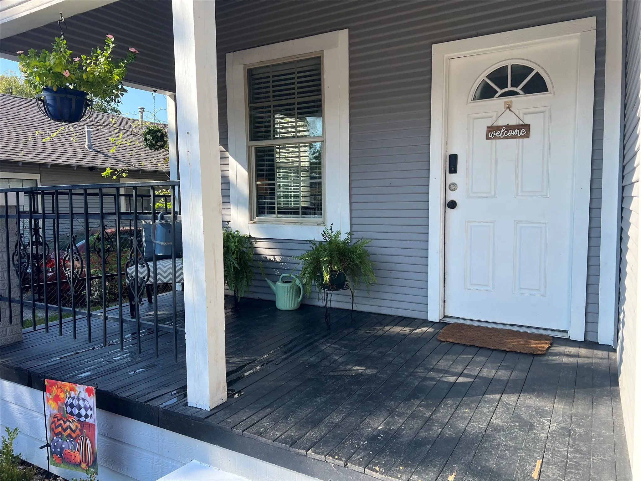 Front porch with gray siding, white trim, and a white paneled door with an arched transom
