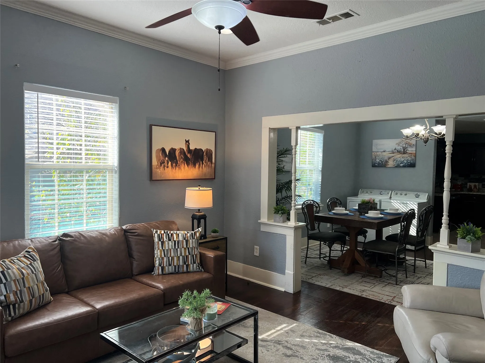 Crown molding details, high ceilings, wood-finish flooring, and a ceiling fan with integrated lighting