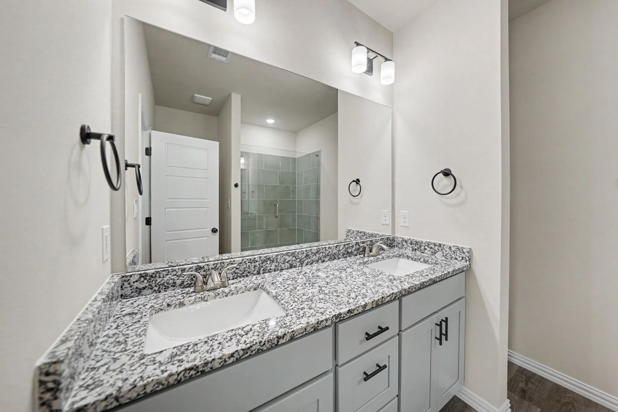 Double vanity with integrated sinks, granite-finish countertop, and undermount cabinetry with matte black hardware