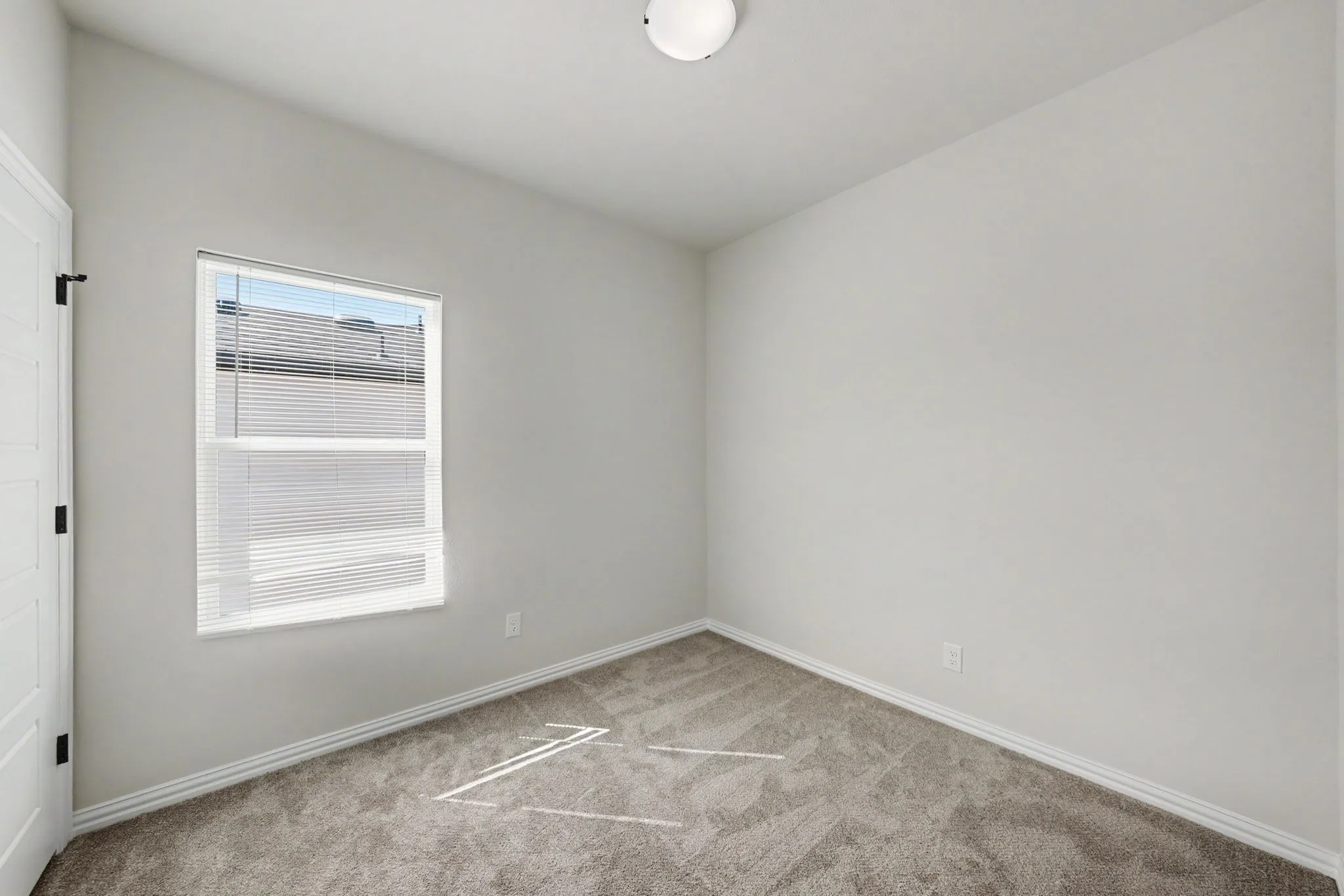 Neutral wall paint, carpeted flooring, white trim, and a flush mount ceiling light